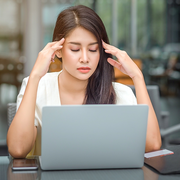 a woman with her hands on her head looking at a laptop