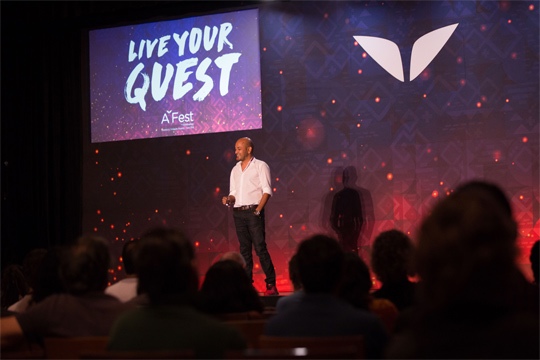 Ajit-Giving-a-Speech-in-front-of-300-people-at-A-Fest-Mexico-2016-1 a person standing on a stage with a crowd watching